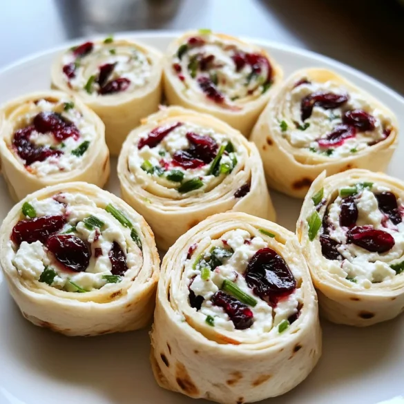 A plate of Cranberry Feta Pinwheels with Cream Cheese, garnished with fresh herbs, ready to be served.
